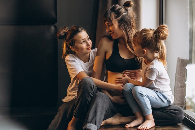 Donna incinta con bambini seduti vicino alla finestra