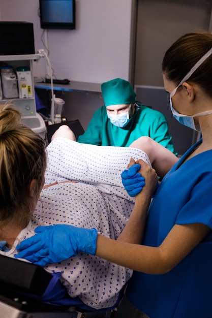 Donna incinta d'esame del gruppo di medici durante la consegna