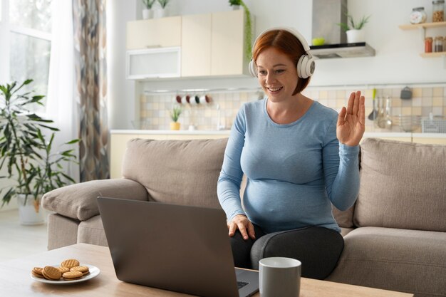 Donna incinta del colpo medio che lavora a distanza