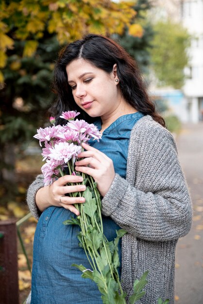 Donna incinta del colpo medio che posa con i fiori