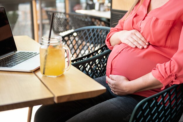 Donna incinta del primo piano ad un terrazzo con succo