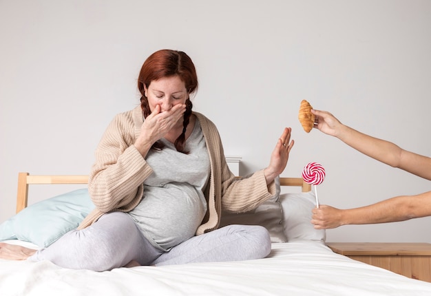 Donna incinta di angolo basso che rifiuta gli spuntini