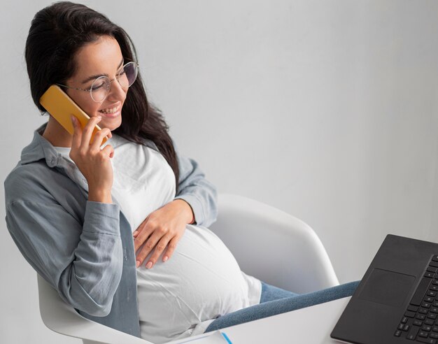 Donna incinta di smiley a casa parlando al telefono