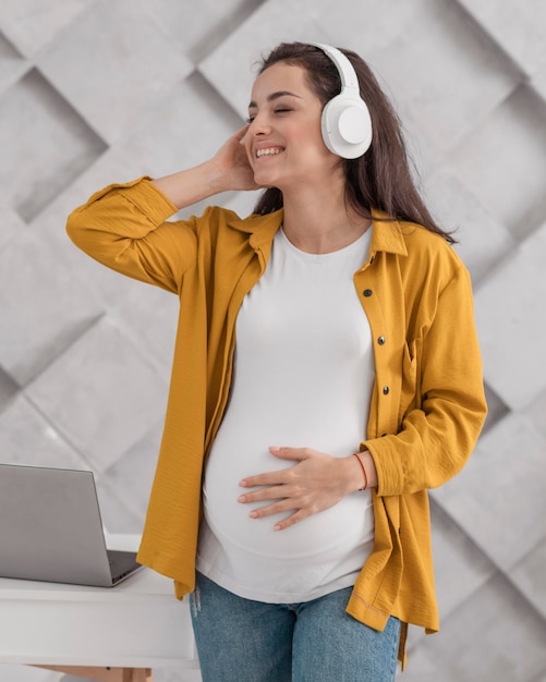 Donna incinta di smiley che ascolta la musica sulle cuffie