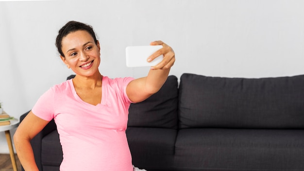 Donna incinta di smiley prendendo selfie a casa durante l'allenamento