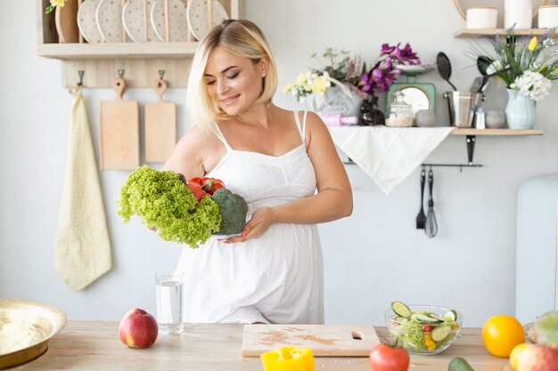 Donna incinta di vista frontale che produce un'insalata