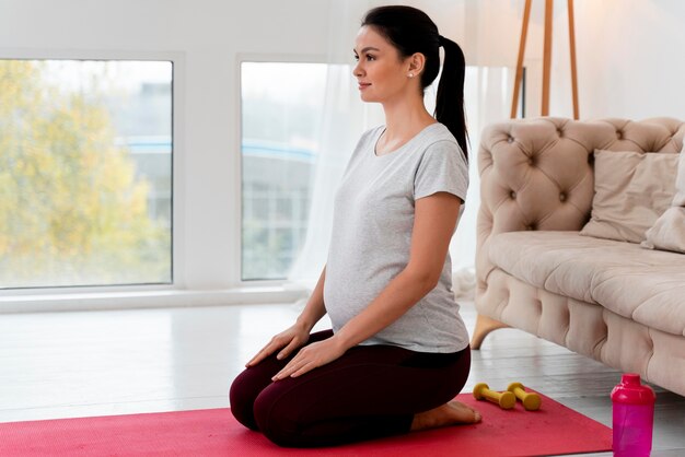 Donna incinta di vista laterale che fa yoga