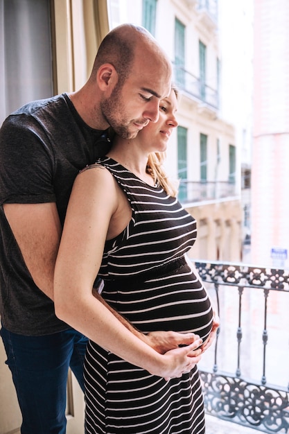 Donna incinta e marito davanti alla finestra