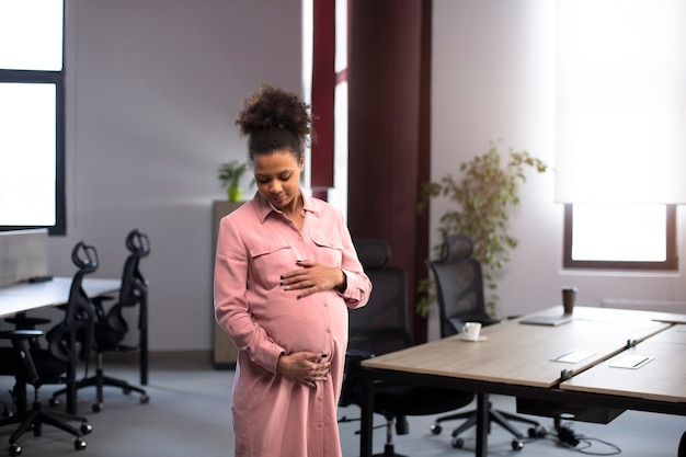 Donna incinta felice del colpo medio al lavoro