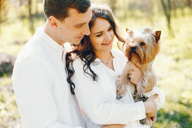 donna incinta luminosa e felice che cammina nel parco con il marito e il cane