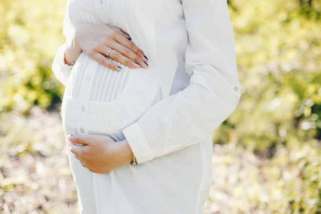 donna incinta luminosa e felice che cammina nel parco soleggiato