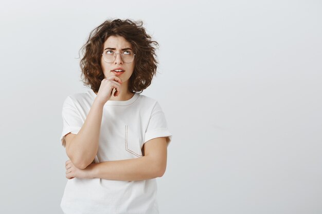 Donna indecisa e perplessa che fa i calcoli, alzando lo sguardo mentre pensa