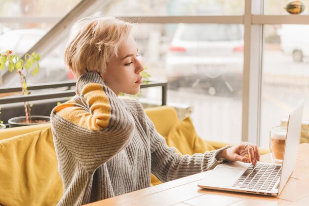 Donna indipendente che lavora con il computer portatile in caffetteria