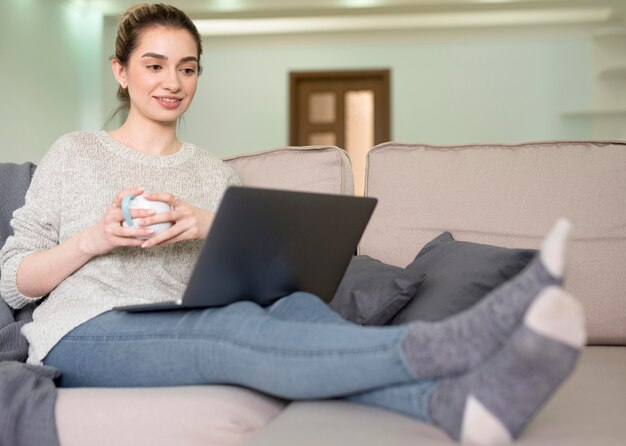 Donna indipendente sul divano che lavora da casa