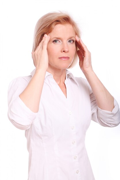 Donna invecchiata centrale che ha dolore alla testa sopra fondo bianco