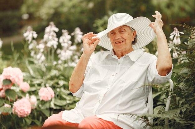 Donna invecchiata che si siede nel parco. Nonna con un cappello bianco.