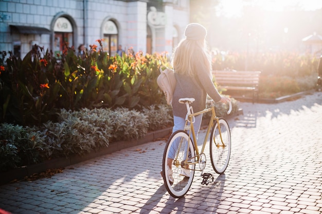 Donna irriconoscibile che cammina con la bicicletta nel parco