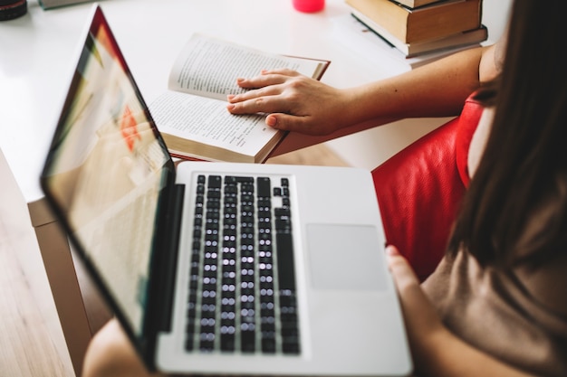 Donna irriconoscibile con il libro di lettura del computer portatile