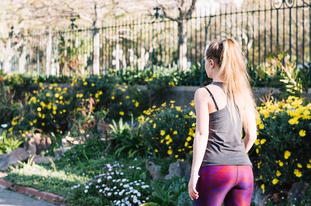 Donna irriconoscibile in abiti sportivi che camminano nel parco