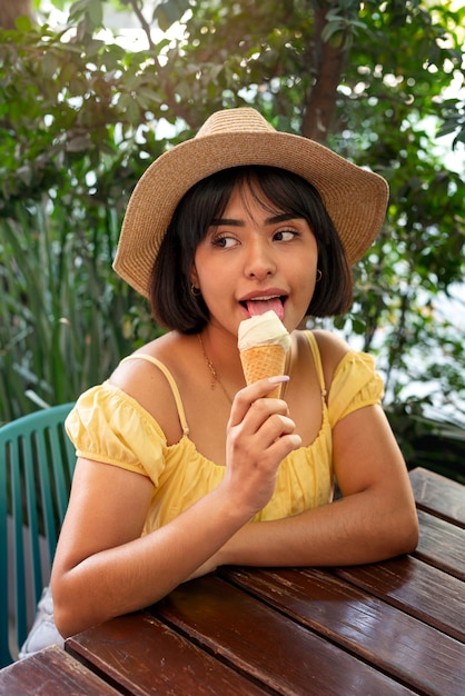 Donna ispanica del colpo medio che mangia il gelato