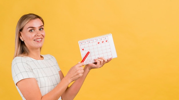 Donna laterale che mostra il suo calendario mestruale