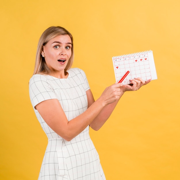 Donna lateralmente in abito bianco tenendo il calendario periodo