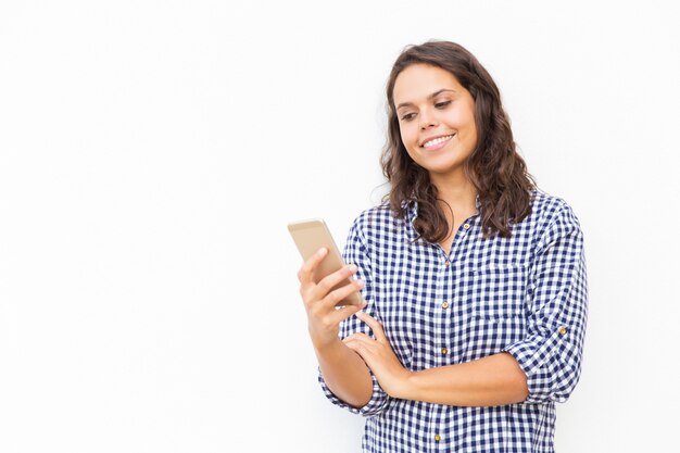 Donna latina positiva allegra con il messaggio della lettura dello smartphone
