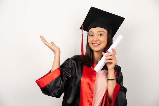 Donna laureata fresca con diploma in posa su sfondo bianco.