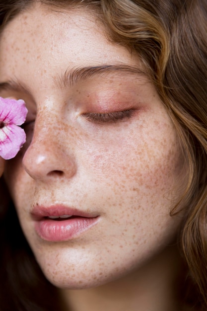 Donna lentigginosa che copre l'occhio con un fiore