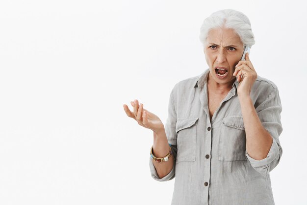Donna maggiore arrabbiata che grida mentre parla sul telefono cellulare