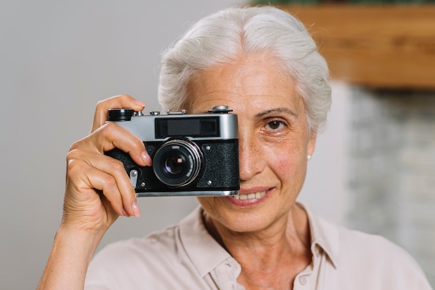 Donna maggiore che cattura maschera con la macchina fotografica