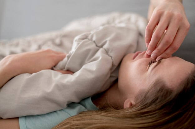 Donna malata che si siede nel letto e che copre il viso