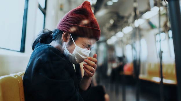 Donna malata con una maschera che starnutisce in un treno durante la pandemia di coronavirus