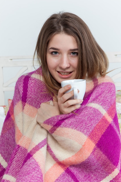 Donna malata coperta di coperta che tiene tazza di tè