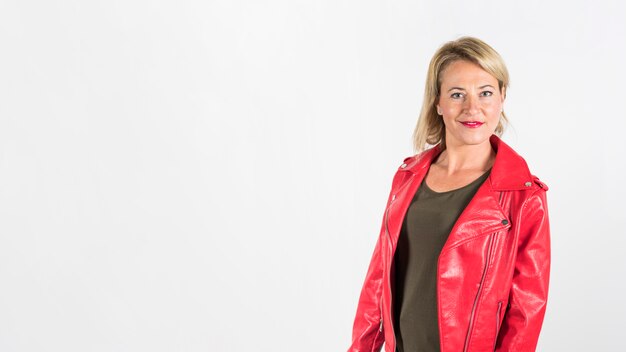 Donna matura bionda alla moda in bomber rosso contro fondo bianco