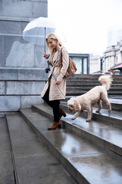 Donna matura che porta a spasso il suo cane in città mentre piove