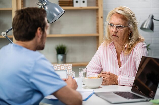 Donna matura seria che parla con il medico dopo l'esame medico presso l'ufficio del medico