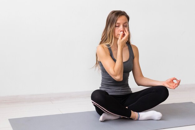 Donna meditando su un tappetino fitness con copia spazio