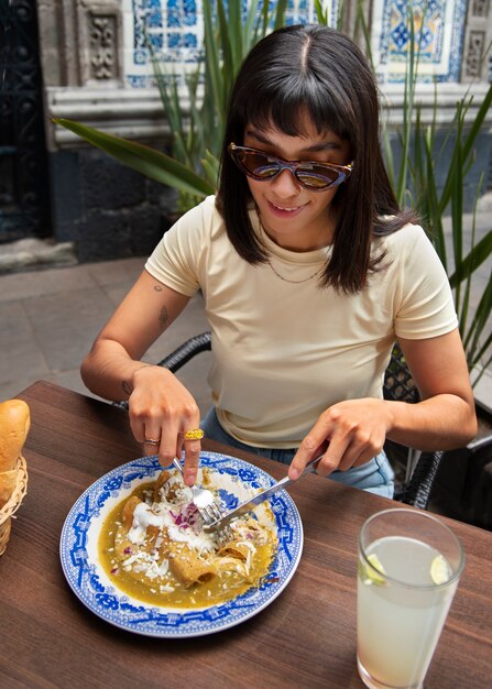 Donna messicana del colpo medio che mangia alimento di ranchero