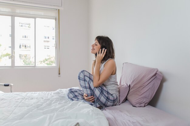 Donna moderna che comunica sul telefono sul letto
