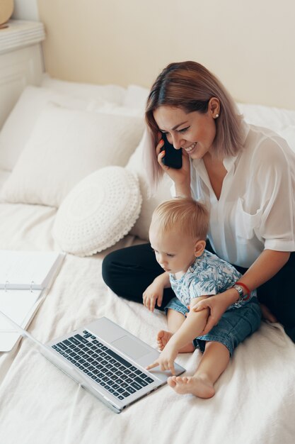 Donna moderna che lavora con il bambino. Concetto multi-tasking, freelance e maternità