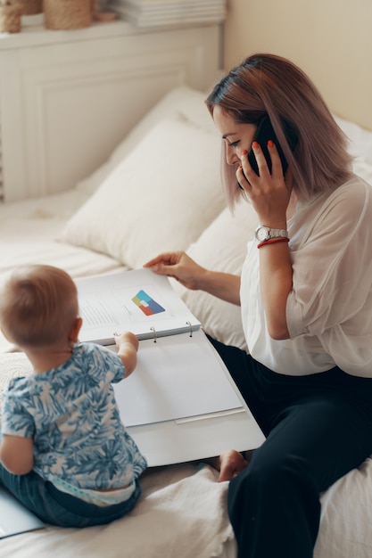 Donna moderna che lavora con il bambino. Concetto multi-tasking, freelance e maternità