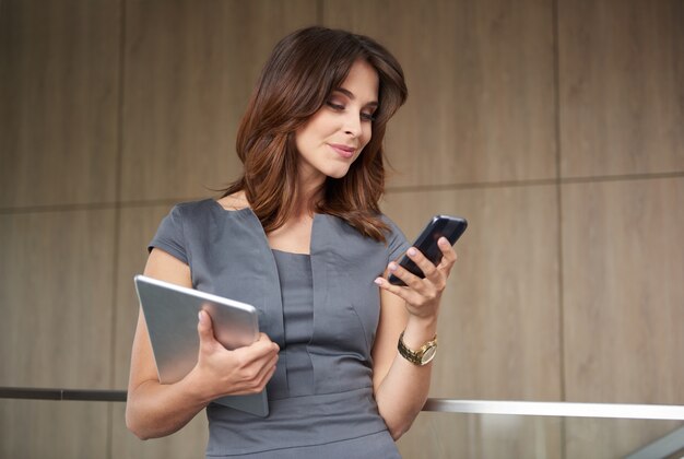 Donna moderna con telefono e tablet digitale