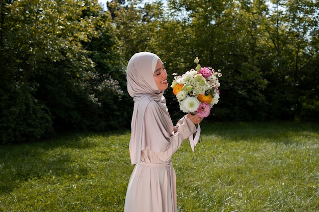 Donna musulmana del colpo medio che posa con i fiori