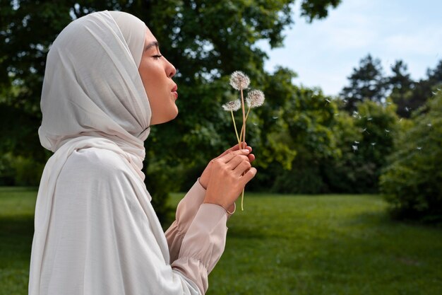 Donna musulmana del colpo medio che posa con i fiori