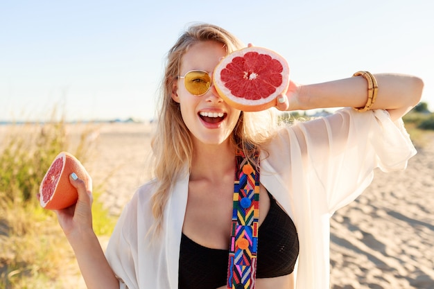 Donna naturale bionda felice che tiene pompelmo .Alimento dieta sana. Vacanze estive .