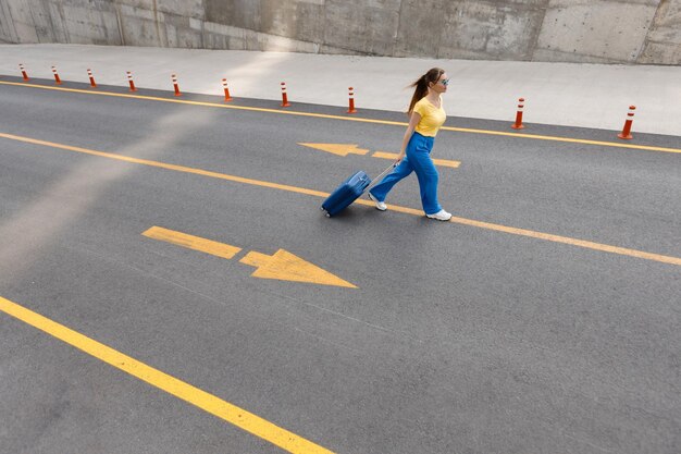 donna nei colori della bandiera ucraina sulla strada con la valigia