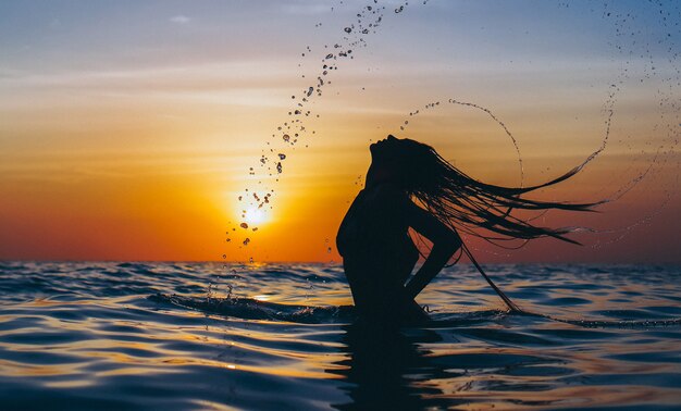Donna nell'oceano nell'ora del tramonto