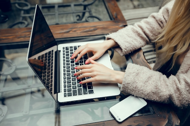 Donna nella caffetteria con computer portatile e telefono