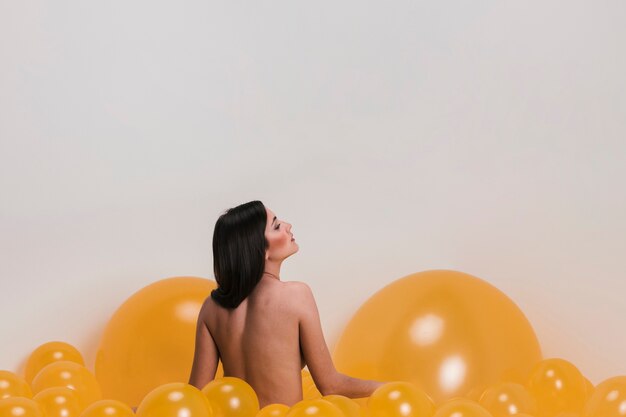 Donna nuda tra molti palloncini gialli